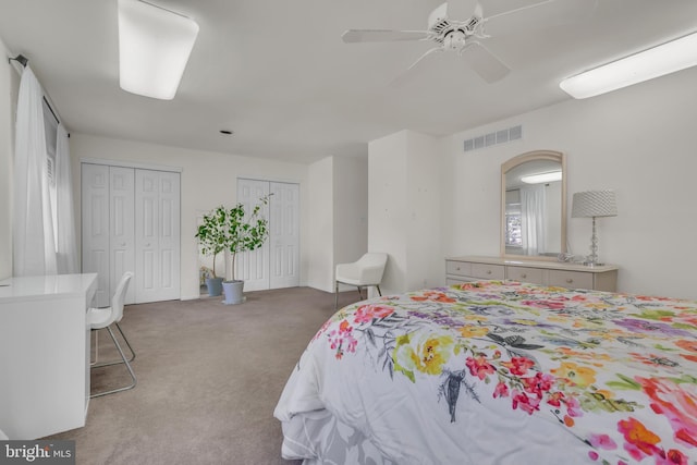 bedroom featuring ceiling fan, multiple closets, and carpet flooring