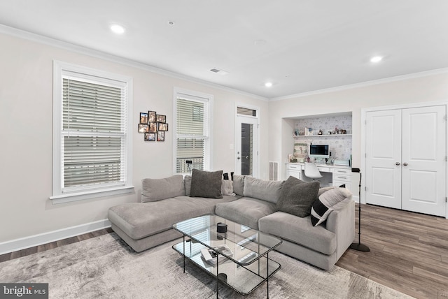 living room with a wealth of natural light, hardwood / wood-style flooring, and crown molding