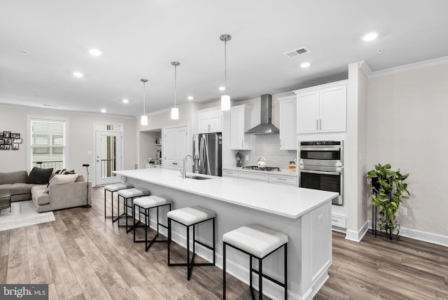 kitchen with stainless steel appliances, a large island, white cabinetry, wall chimney exhaust hood, and a breakfast bar