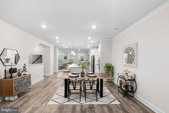 dining area with light hardwood / wood-style floors and crown molding