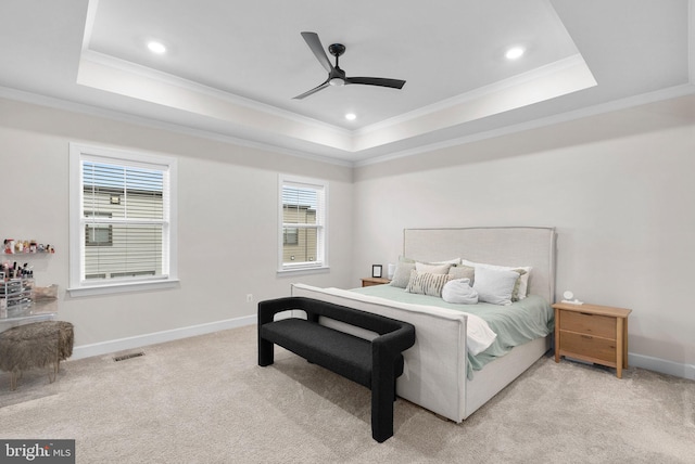 bedroom with ceiling fan, light carpet, and a tray ceiling