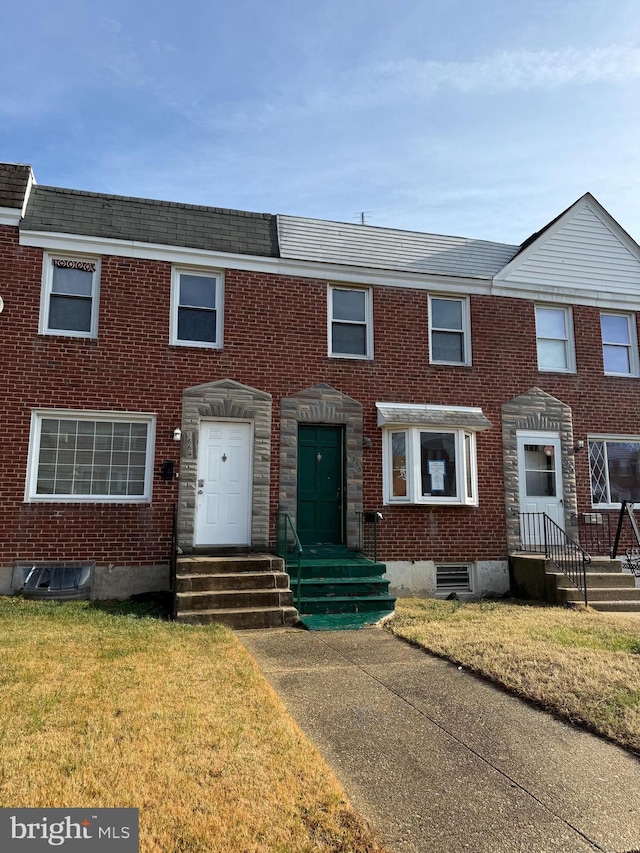 multi unit property with brick siding and a front yard