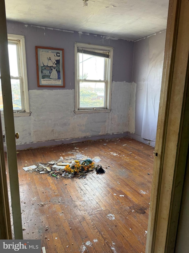 empty room with hardwood / wood-style flooring and a healthy amount of sunlight