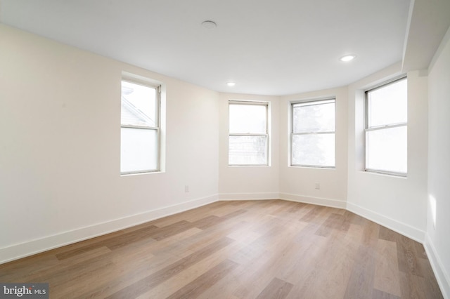 empty room with light hardwood / wood-style flooring and plenty of natural light