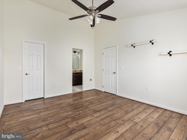 unfurnished bedroom with a towering ceiling, ensuite bathroom, ceiling fan, and dark hardwood / wood-style floors