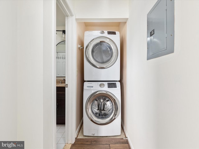 laundry area featuring electric panel and stacked washer and dryer