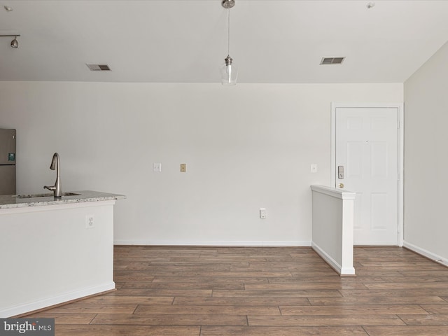 interior space with sink, dark hardwood / wood-style flooring, pendant lighting, and light stone counters