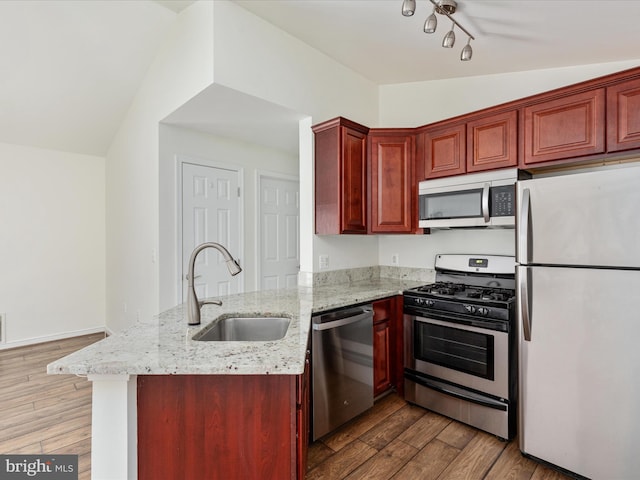 kitchen featuring appliances with stainless steel finishes, sink, light stone counters, and kitchen peninsula