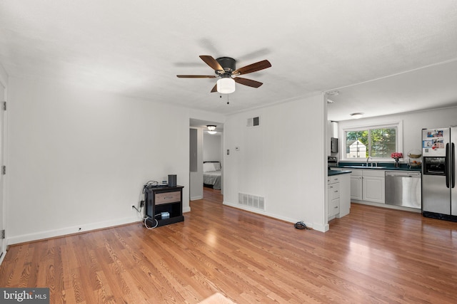 unfurnished living room featuring ceiling fan, sink, and light hardwood / wood-style floors