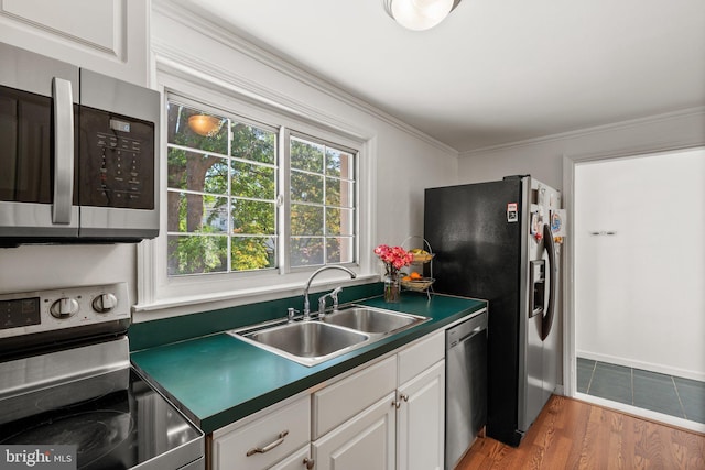 kitchen featuring white cabinetry, sink, stainless steel appliances, light hardwood / wood-style flooring, and ornamental molding