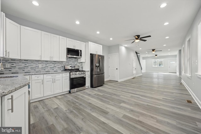 kitchen featuring white cabinetry, decorative backsplash, appliances with stainless steel finishes, and light stone counters