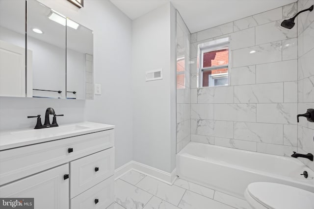 full bathroom featuring tiled shower / bath, vanity, and toilet