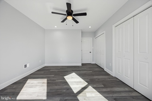 unfurnished bedroom featuring dark hardwood / wood-style floors, two closets, and ceiling fan