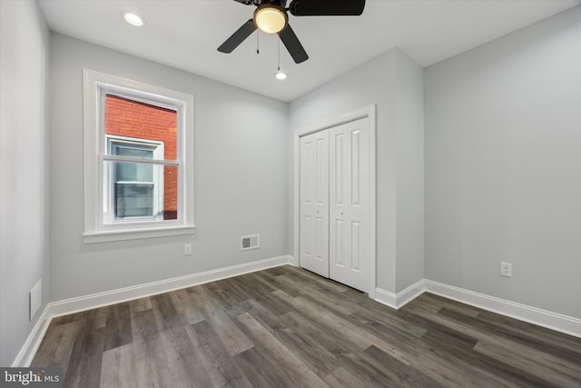 unfurnished bedroom featuring ceiling fan, dark hardwood / wood-style flooring, and a closet