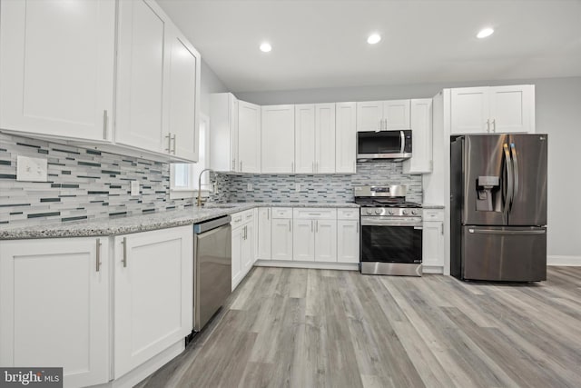 kitchen with light stone counters, stainless steel appliances, white cabinets, and light wood-type flooring