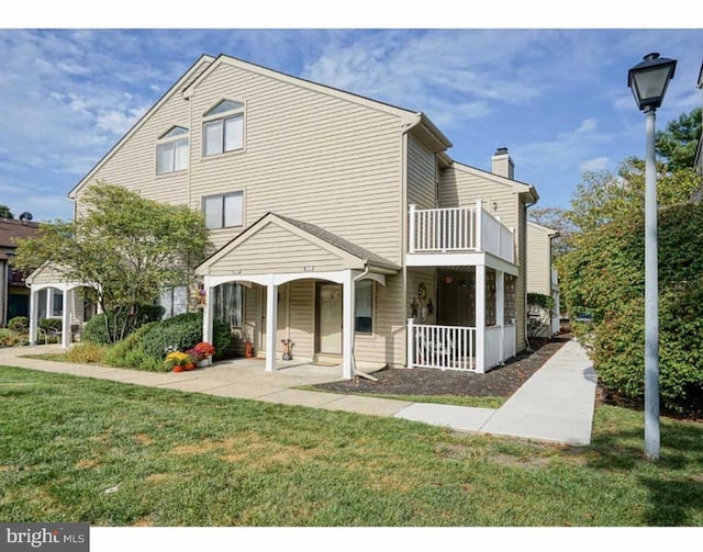 view of front of property featuring covered porch, a balcony, and a front lawn