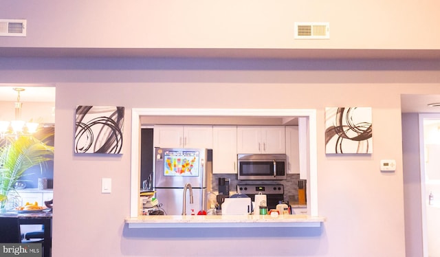 kitchen featuring a notable chandelier, white cabinetry, and appliances with stainless steel finishes