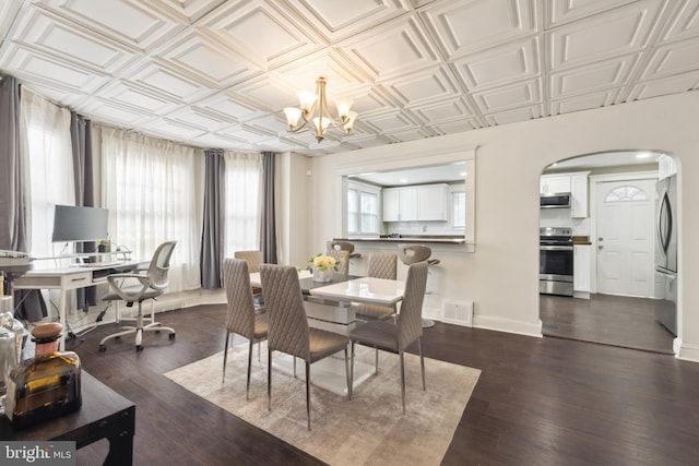 dining space featuring dark wood-type flooring and an inviting chandelier