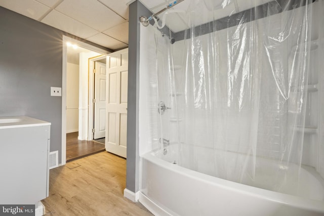 bathroom featuring hardwood / wood-style floors, a drop ceiling, shower / bathtub combination with curtain, and vanity