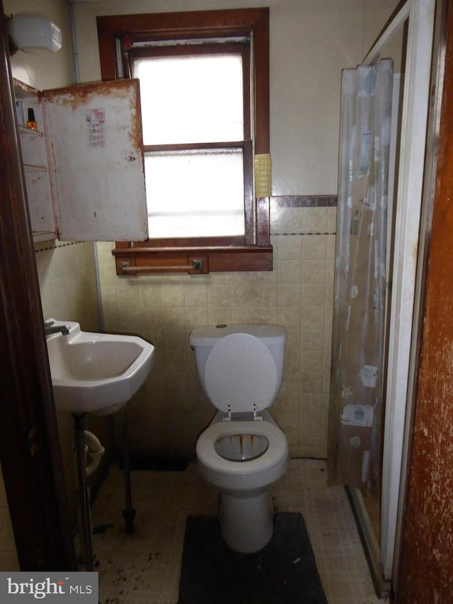 bathroom featuring toilet, tile walls, tile patterned floors, and a shower with shower curtain