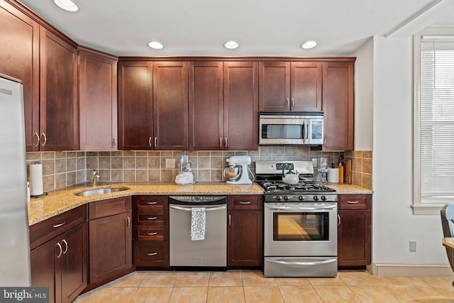 kitchen with light stone counters, light tile patterned floors, sink, and appliances with stainless steel finishes