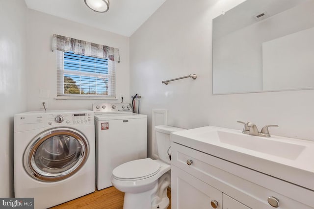 bathroom featuring toilet, hardwood / wood-style flooring, washer and clothes dryer, and vanity