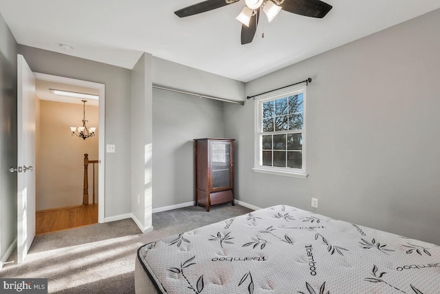 carpeted bedroom featuring ceiling fan with notable chandelier and a closet