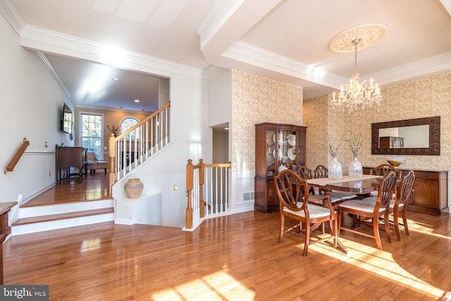 dining space featuring ornamental molding, hardwood / wood-style floors, and a notable chandelier