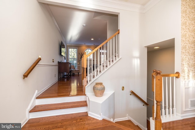 stairway with hardwood / wood-style flooring and ornamental molding