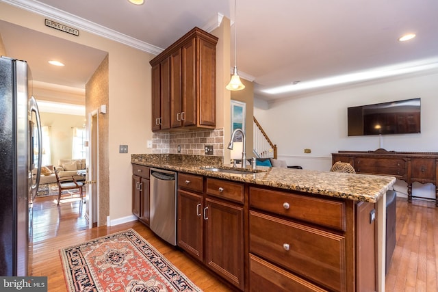 kitchen featuring sink, crown molding, appliances with stainless steel finishes, hanging light fixtures, and kitchen peninsula