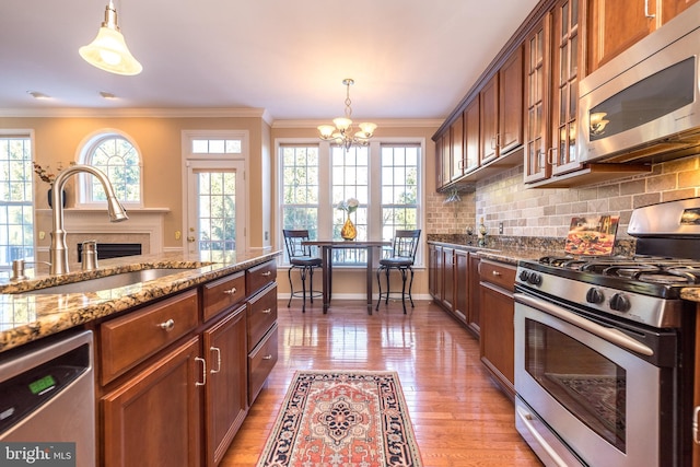 kitchen featuring pendant lighting, sink, stainless steel appliances, light stone counters, and tasteful backsplash