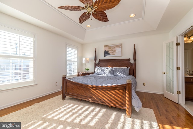 bedroom featuring hardwood / wood-style flooring, ceiling fan, a tray ceiling, and crown molding