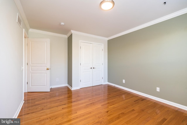 unfurnished bedroom featuring hardwood / wood-style floors, ornamental molding, and a closet