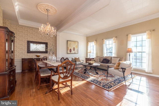 dining area featuring hardwood / wood-style flooring, ornamental molding, and a notable chandelier