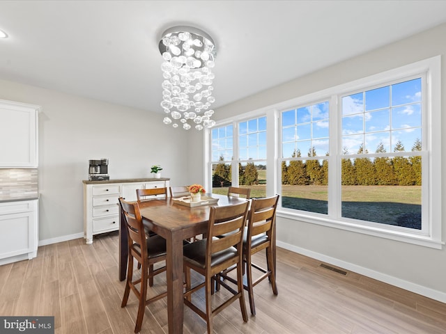 dining room featuring an inviting chandelier, baseboards, visible vents, and light wood-style floors