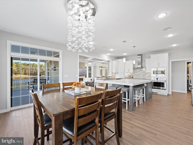 dining room featuring light wood-type flooring, an inviting chandelier, baseboards, and recessed lighting