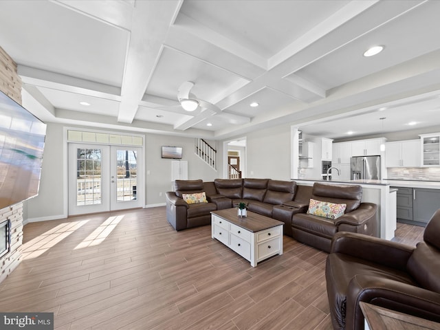 living area with beam ceiling, french doors, stairway, wood finished floors, and baseboards