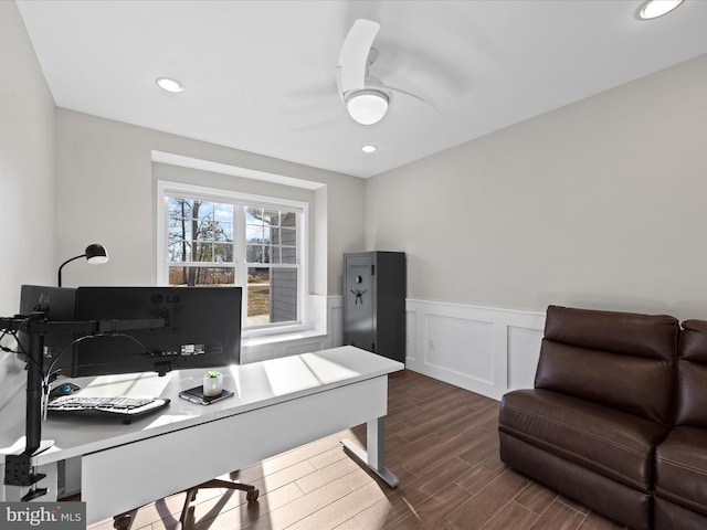 home office featuring ceiling fan, a decorative wall, recessed lighting, wood finish floors, and wainscoting