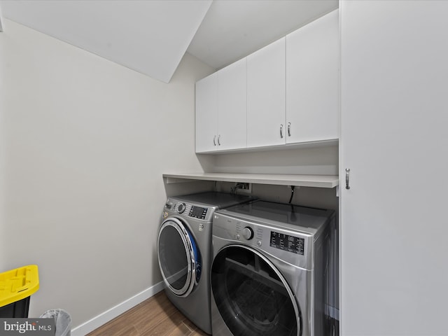 laundry room featuring washer and dryer, cabinet space, baseboards, and wood finished floors