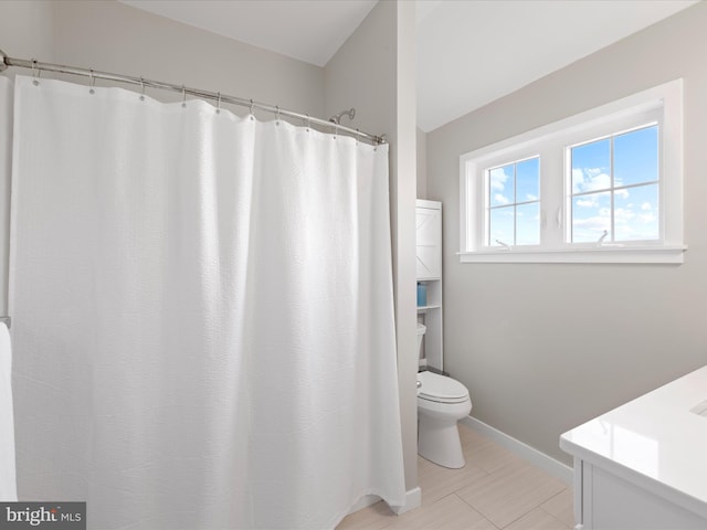 bathroom featuring toilet, baseboards, and vanity