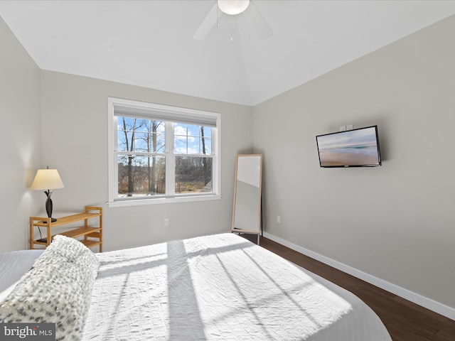 bedroom with dark wood-type flooring, vaulted ceiling, baseboards, and a ceiling fan