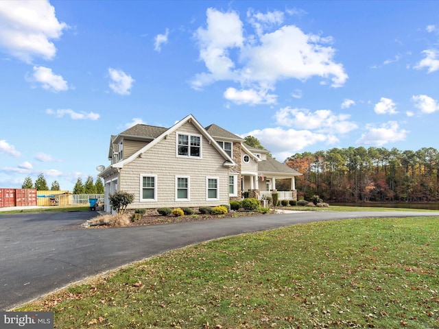 view of front of house with driveway, a front lawn, a porch, and fence