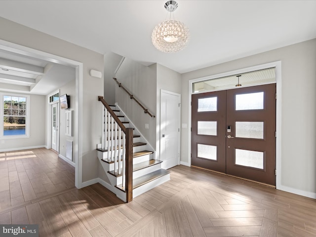 foyer with a chandelier, stairway, wood finished floors, and baseboards