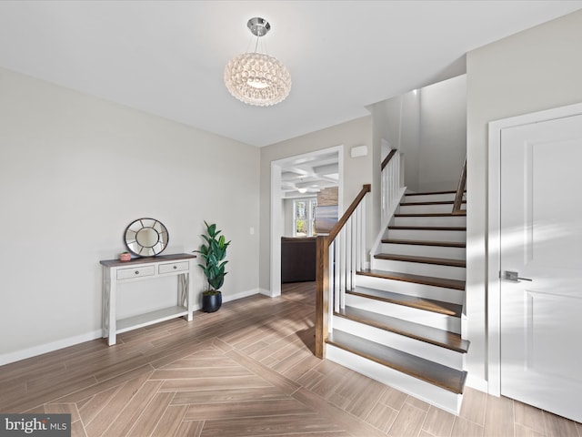 entrance foyer with a notable chandelier, stairway, parquet flooring, and baseboards