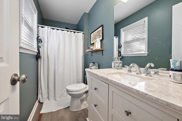 bathroom with a healthy amount of sunlight, vanity, hardwood / wood-style flooring, and toilet