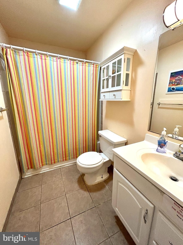 bathroom with toilet, vanity, and tile patterned floors