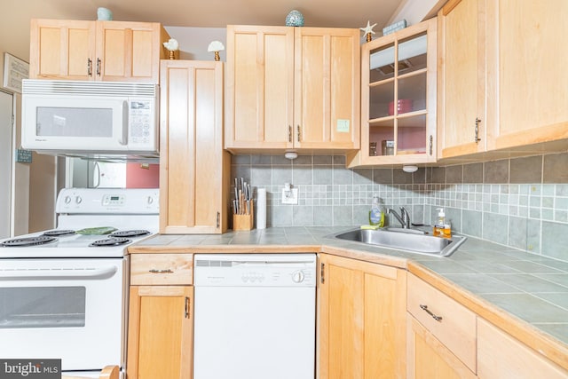 kitchen with white appliances, tile countertops, backsplash, and sink