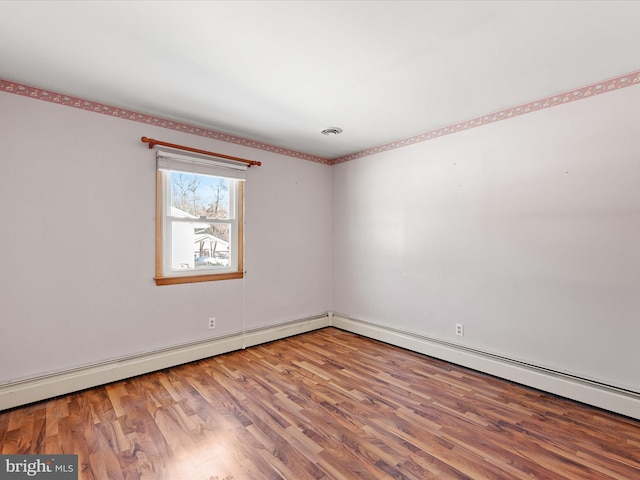 unfurnished room with hardwood / wood-style flooring and a baseboard heating unit