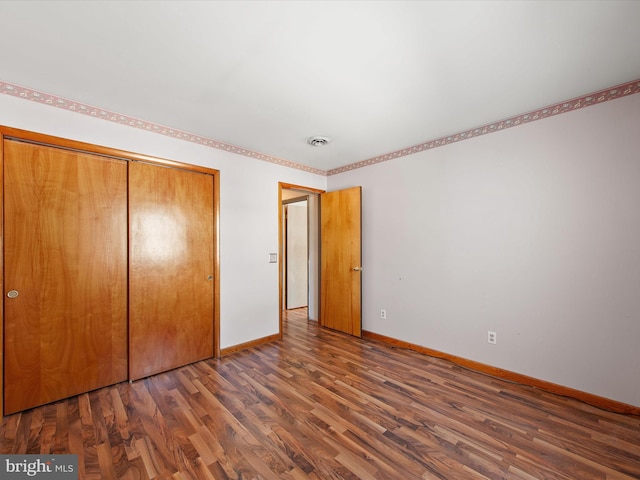 unfurnished bedroom with a closet and dark hardwood / wood-style floors