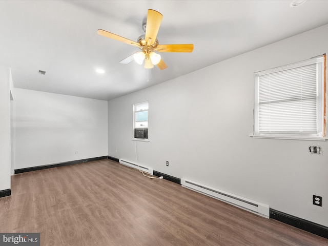 spare room featuring ceiling fan, a baseboard heating unit, and hardwood / wood-style flooring